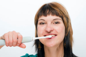 Attractive Woman brushing teeth with electric tooth brush